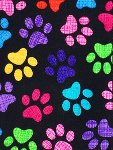Rainbow paw print dog bandana with black background and purple velvet lining.