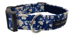 Washable fabric dog collar in a pretty white and orange floral design on a denim blue background.