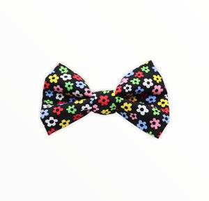 Handmade dog bow tie in cotton print. Made by hand in the U.K. and washable. Black background with multicoloured ditsy daisies. 